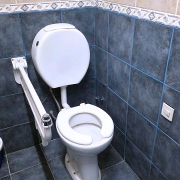 Baño completo y adaptado para movilidad reducida en la residencia geriátrica Casa Trapiche, con ducha a ras de suelo y barras de apoyo.